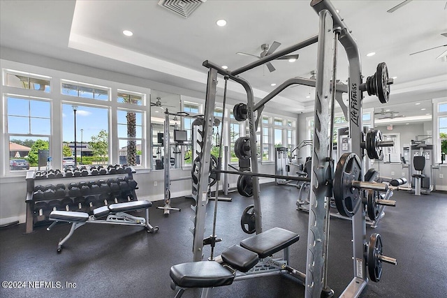 workout area with a raised ceiling and ceiling fan