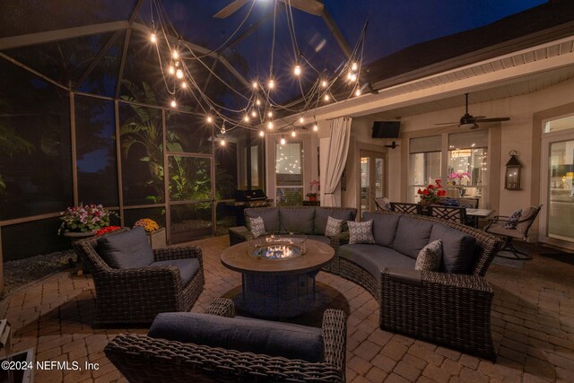 patio at night with an outdoor living space with a fire pit and ceiling fan