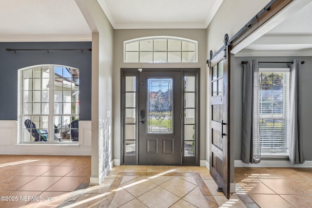 entrance foyer with ornamental molding, a barn door, and light tile patterned flooring