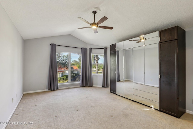 unfurnished bedroom with lofted ceiling, light colored carpet, ceiling fan, a textured ceiling, and a closet