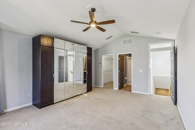 unfurnished bedroom with ceiling fan, connected bathroom, light carpet, vaulted ceiling, and a closet