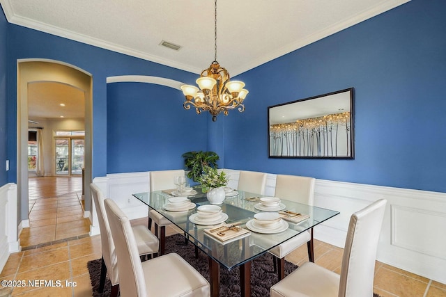 dining room featuring light tile patterned flooring, ornamental molding, and an inviting chandelier