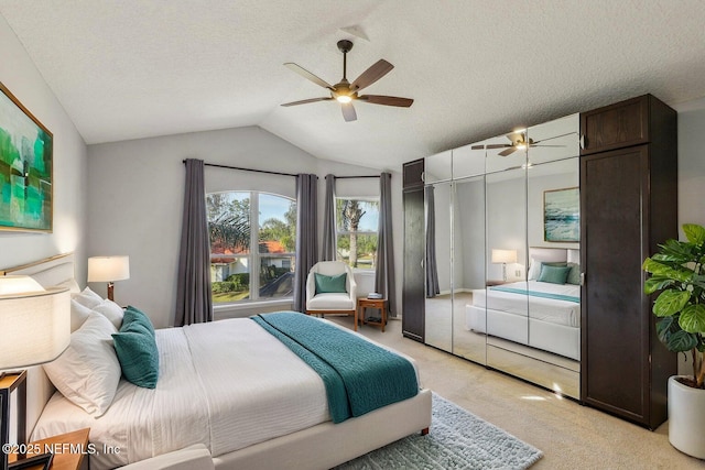 bedroom featuring lofted ceiling, a textured ceiling, light carpet, and ceiling fan