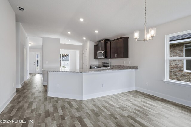 3145 Forest View Ln, Green Cove Springs, FL 32043 - kitchen with stainless steel appliances, a chandelier, light wood finished floors, dark brown cabinetry, and lofted ceiling