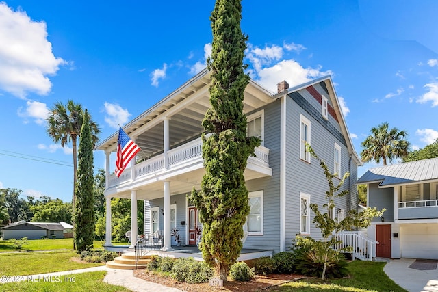 view of front facade with a balcony, a front yard, a garage, and covered porch