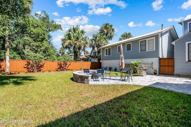 back of house with an outdoor fire pit, a patio, and a lawn