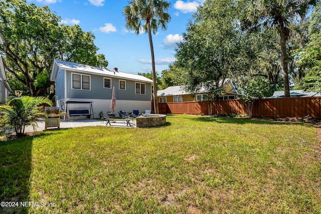 back of house featuring a patio area, a lawn, and a fire pit