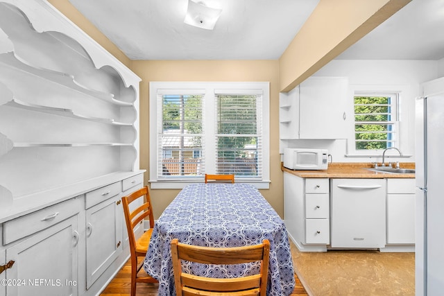 kitchen with light hardwood / wood-style floors, a wealth of natural light, sink, and white appliances