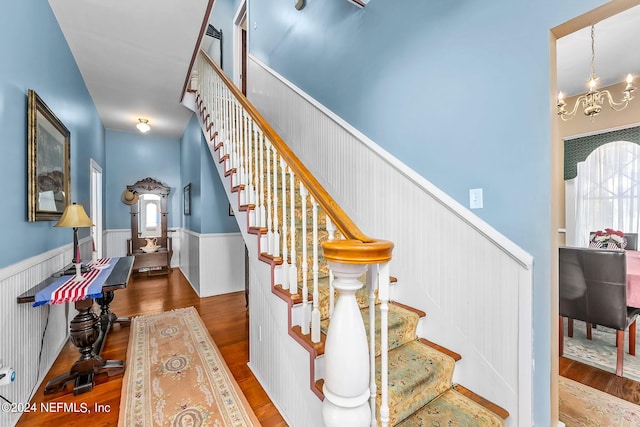 staircase with hardwood / wood-style flooring and a chandelier