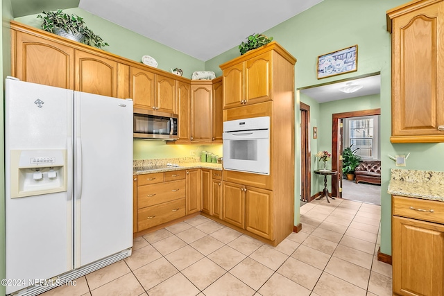 kitchen with white appliances, light stone counters, lofted ceiling, and light tile patterned flooring