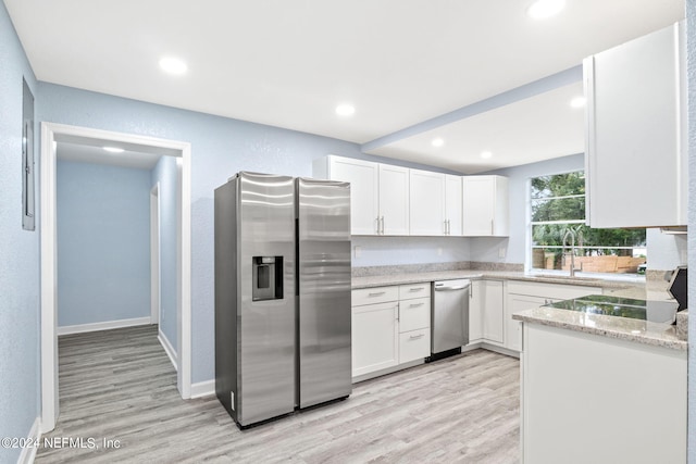 kitchen with light stone countertops, stainless steel fridge, white cabinets, and light wood-type flooring