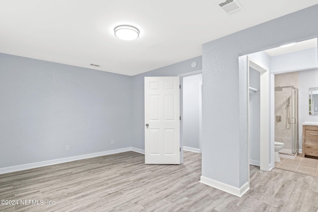 unfurnished bedroom featuring light hardwood / wood-style flooring, a closet, and ensuite bath