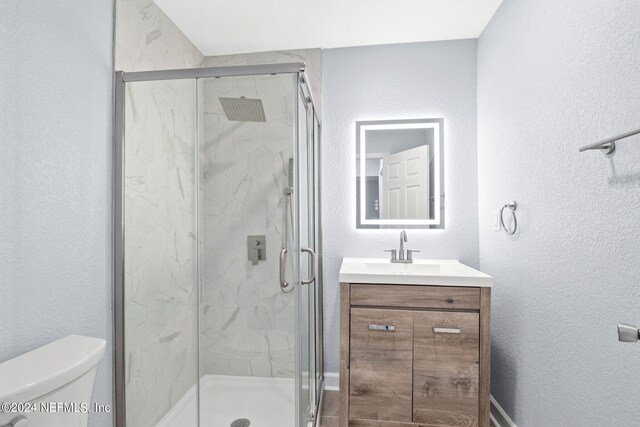 bathroom with toilet, an enclosed shower, and vanity