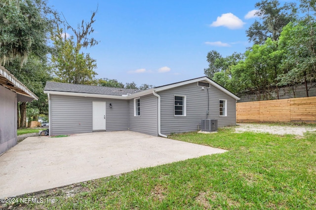 rear view of property with central air condition unit, a patio area, and a yard