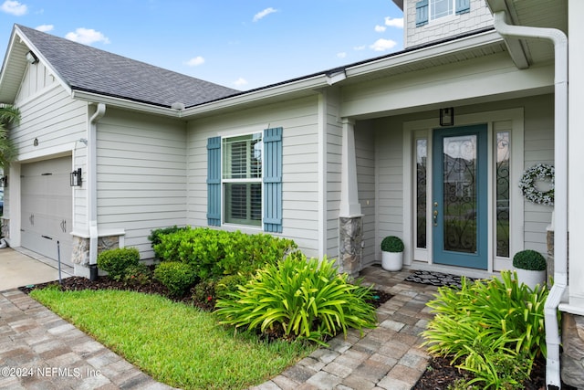 doorway to property with driveway and roof with shingles