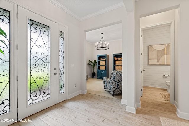 entryway featuring ornamental molding, light hardwood / wood-style floors, and a notable chandelier