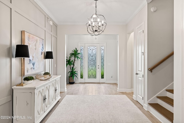 foyer featuring crown molding, light wood-type flooring, and a notable chandelier