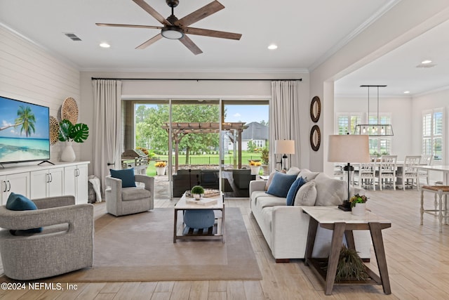 living room with ornamental molding, ceiling fan, and light wood-type flooring