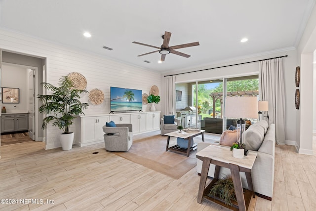 living room featuring ceiling fan, light wood-type flooring, and crown molding