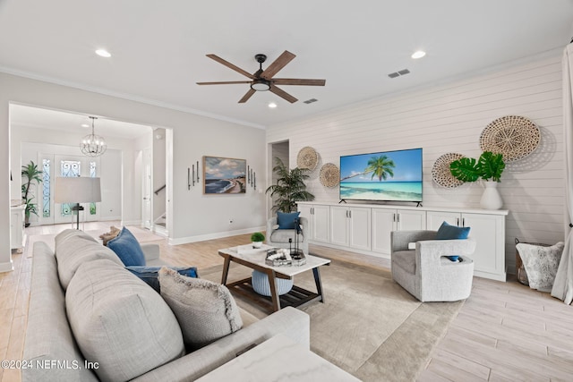 living room with ceiling fan with notable chandelier, light hardwood / wood-style floors, and crown molding