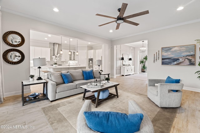 living area featuring crown molding, light wood finished floors, and ceiling fan with notable chandelier