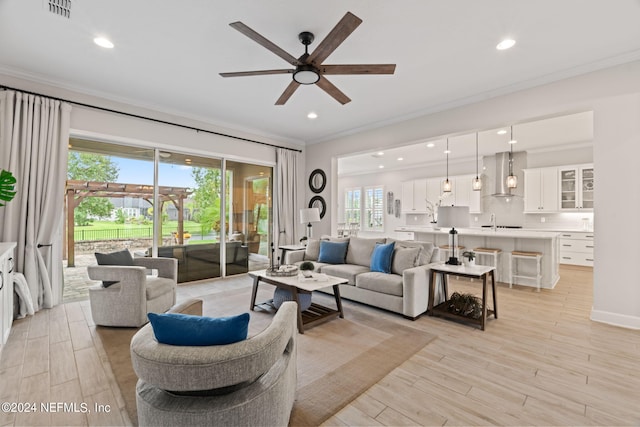 living room featuring ornamental molding, ceiling fan, and sink