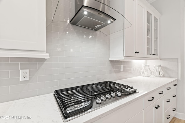 kitchen with white cabinets, decorative backsplash, stainless steel gas cooktop, and ventilation hood