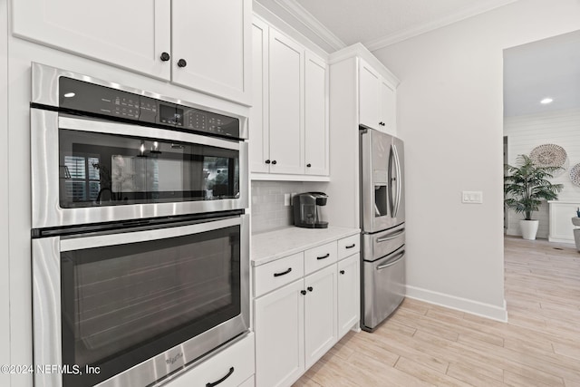 kitchen with stainless steel appliances, white cabinets, backsplash, light stone countertops, and crown molding