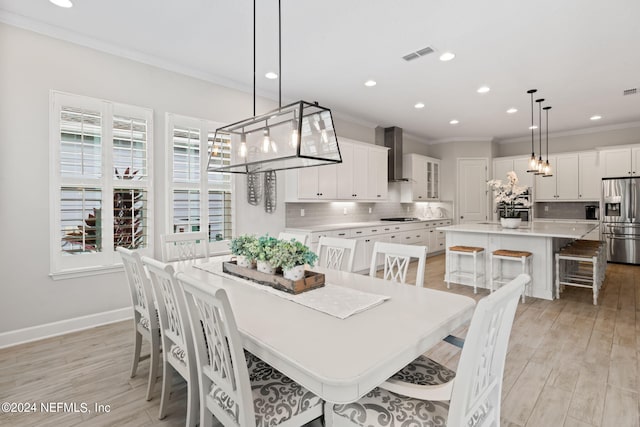 dining area featuring light wood-type flooring and crown molding