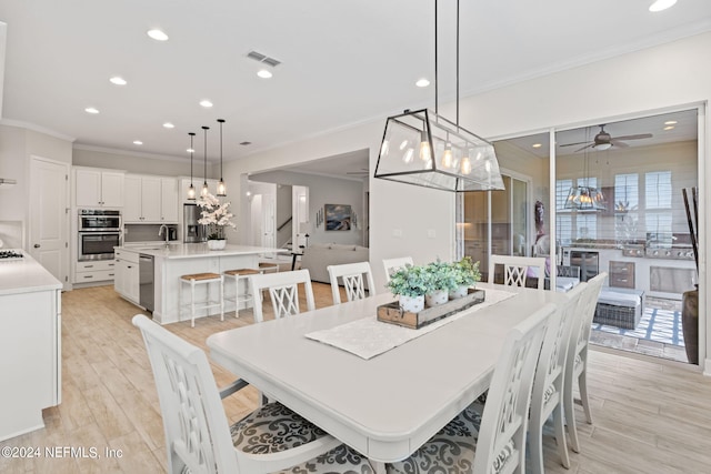 dining space featuring light hardwood / wood-style floors, sink, crown molding, and ceiling fan with notable chandelier