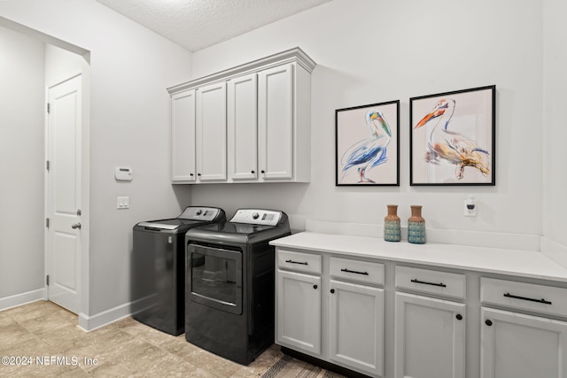 laundry room featuring a textured ceiling, cabinets, and washing machine and dryer