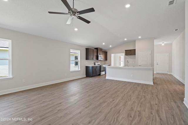 unfurnished living room featuring baseboards, visible vents, lofted ceiling, light wood-style floors, and a sink