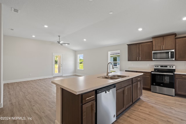 kitchen featuring an island with sink, lofted ceiling, sink, light hardwood / wood-style flooring, and stainless steel appliances