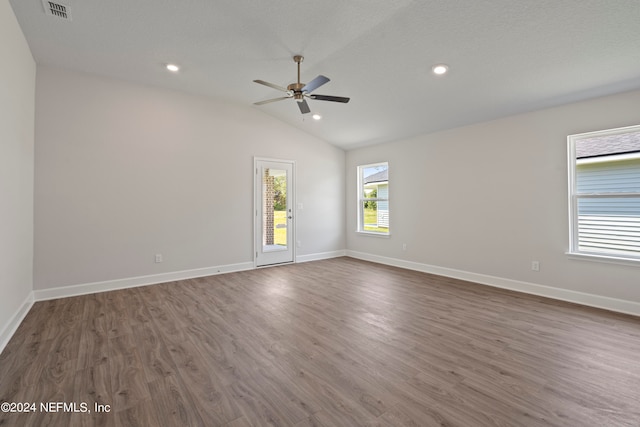 spare room featuring lofted ceiling, ceiling fan, dark wood-type flooring, and a textured ceiling