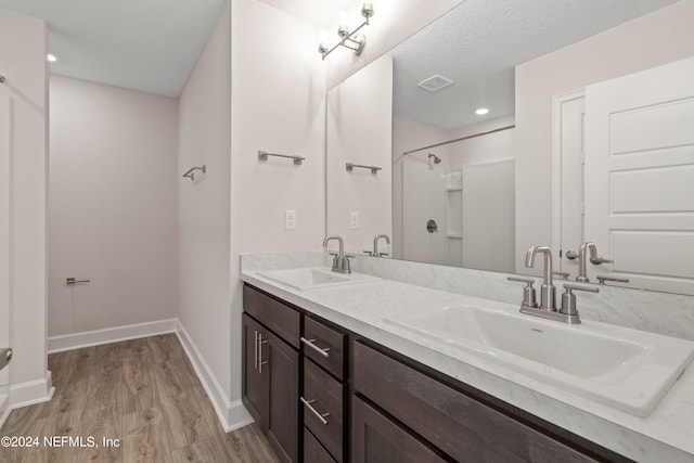 bathroom with walk in shower, a textured ceiling, vanity, and hardwood / wood-style flooring