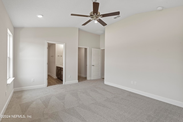 unfurnished bedroom featuring ceiling fan, lofted ceiling, ensuite bath, and carpet