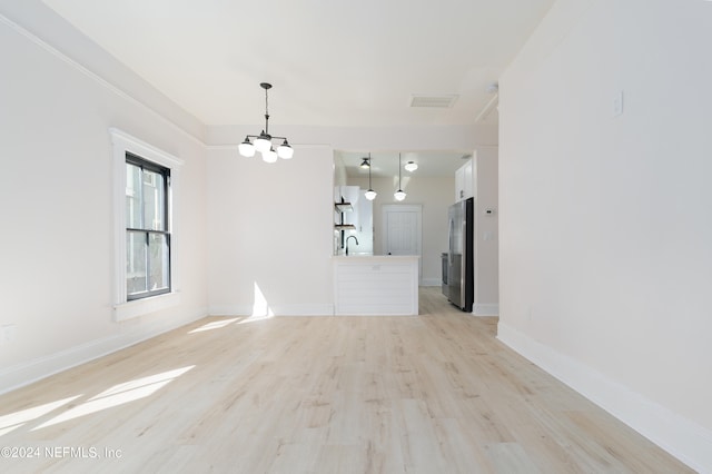 empty room with light hardwood / wood-style flooring, a chandelier, and sink