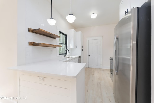 kitchen with white cabinetry, kitchen peninsula, pendant lighting, appliances with stainless steel finishes, and light wood-type flooring