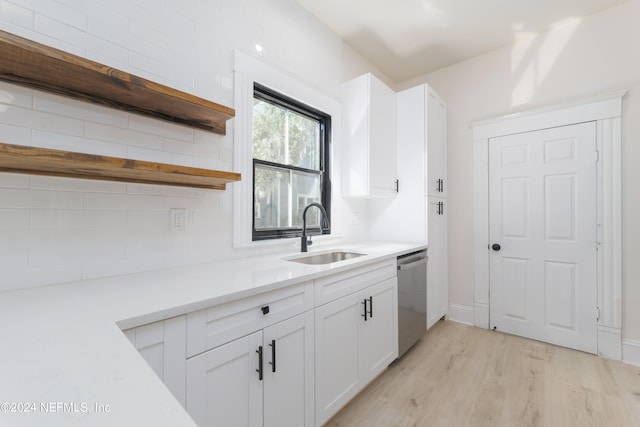 kitchen with dishwasher, backsplash, sink, light wood-type flooring, and white cabinetry