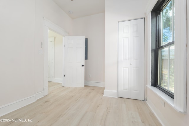 unfurnished bedroom with multiple windows, a closet, light hardwood / wood-style floors, and electric panel