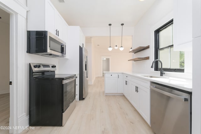 kitchen with white cabinetry, sink, decorative light fixtures, appliances with stainless steel finishes, and light wood-type flooring