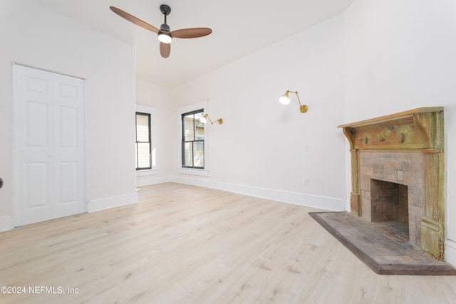 unfurnished living room featuring ceiling fan, a fireplace, and light hardwood / wood-style flooring