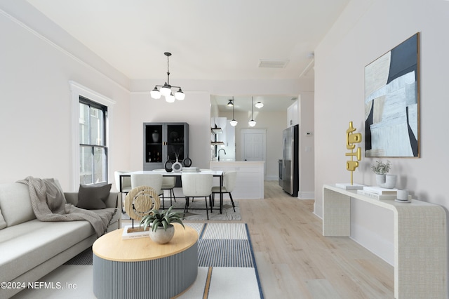 living room featuring a chandelier, sink, and light hardwood / wood-style flooring