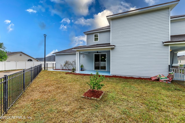 back of house featuring a lawn, ceiling fan, and a patio