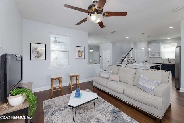 living room featuring dark hardwood / wood-style flooring, ceiling fan, and sink