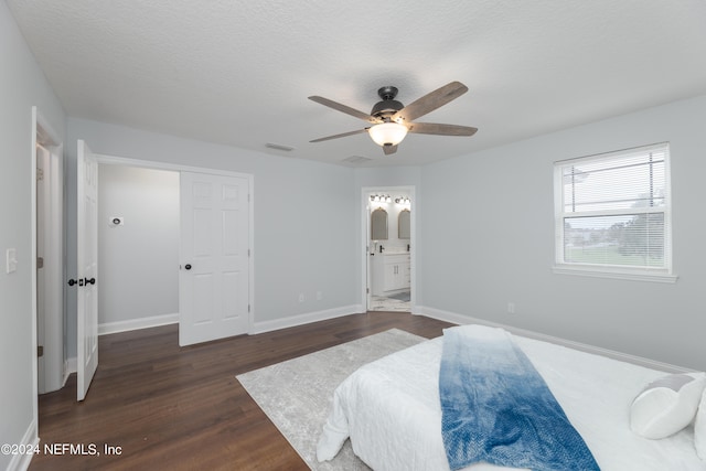 bedroom with ceiling fan, a textured ceiling, a closet, dark hardwood / wood-style floors, and ensuite bathroom