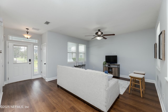 living area featuring visible vents, dark wood finished floors, and baseboards