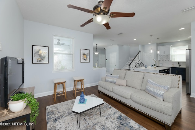 living room with plenty of natural light, stairs, and dark wood finished floors