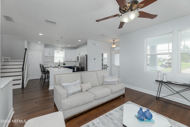 living room with a wealth of natural light, visible vents, and stairs