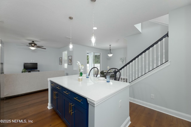 kitchen featuring open floor plan, light countertops, dark wood finished floors, and blue cabinets